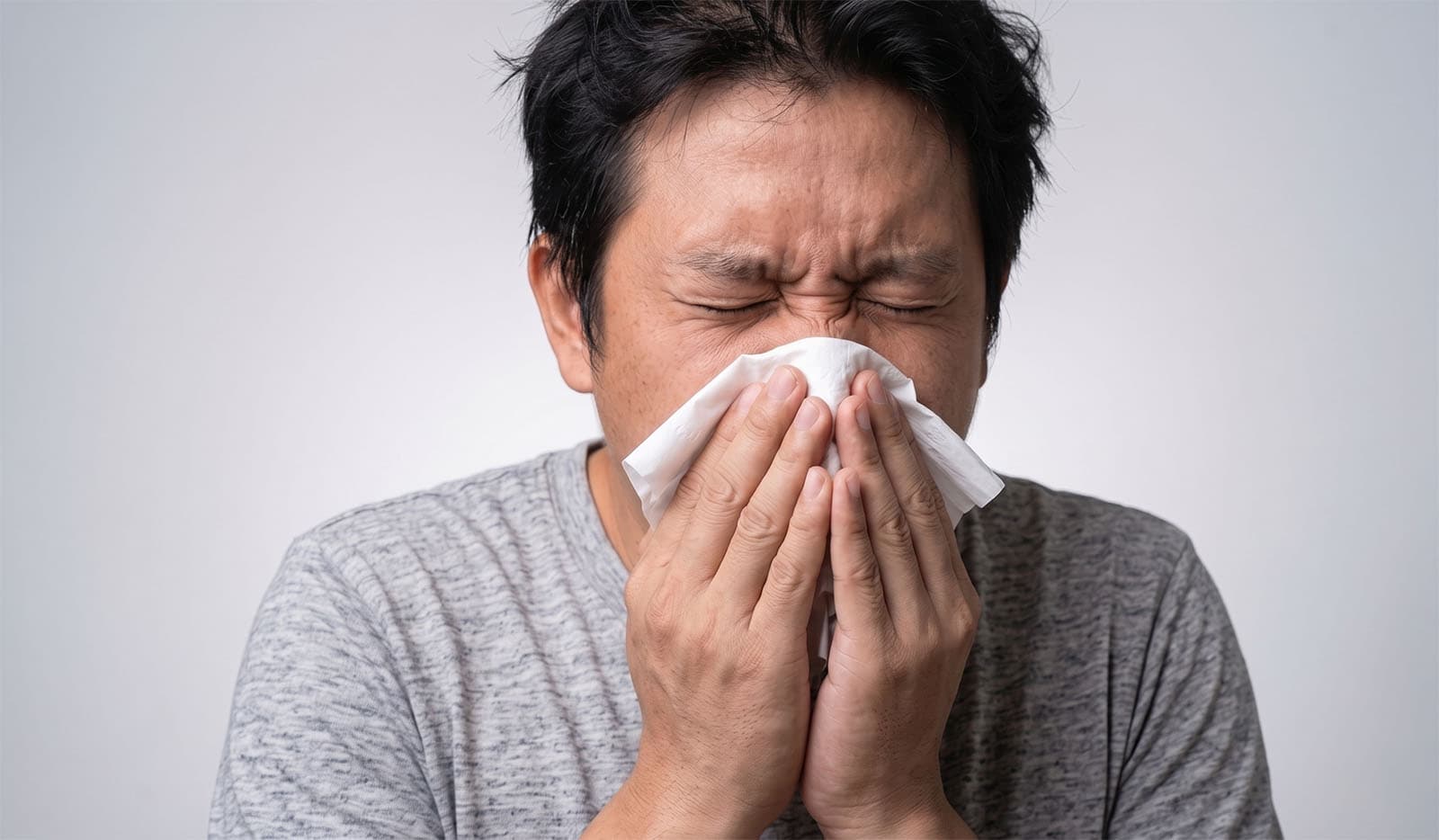 Man sneezing into tissue